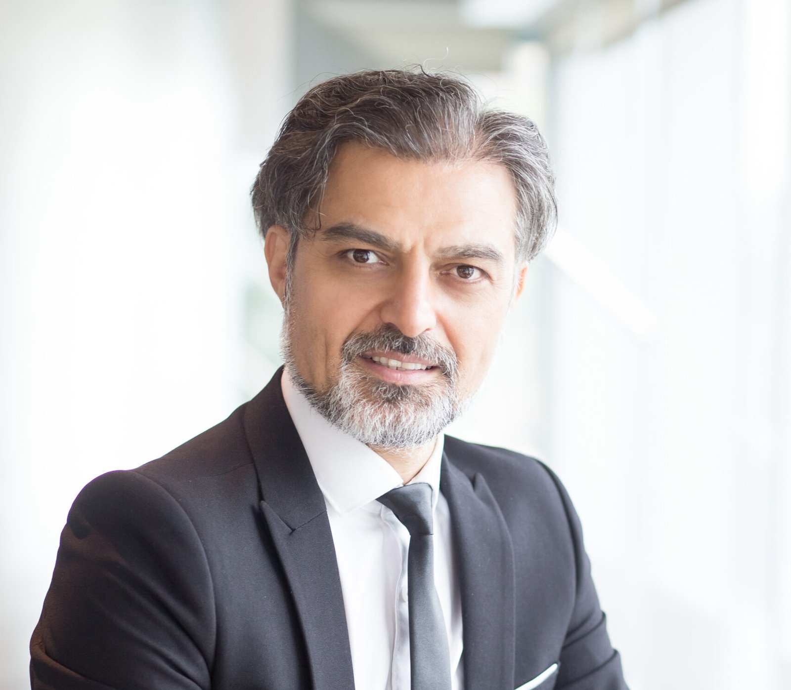 Closeup portrait of confident middle-aged handsome business man looking at camera and sitting at table in office